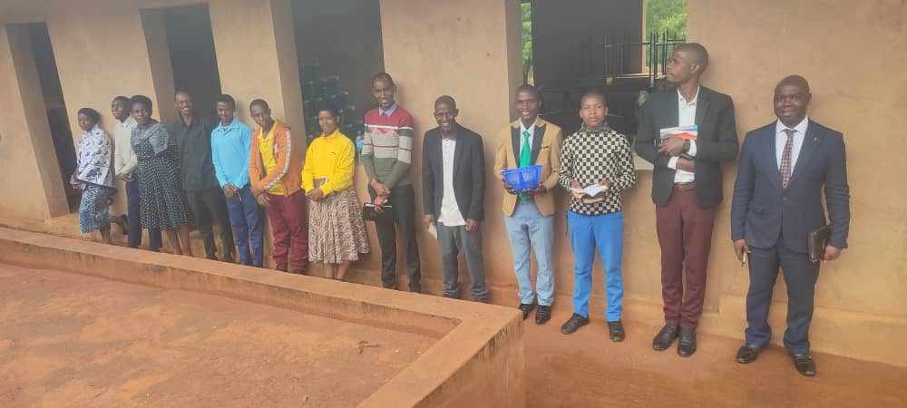 Students standing together outside a classroom building, most holding Bibles